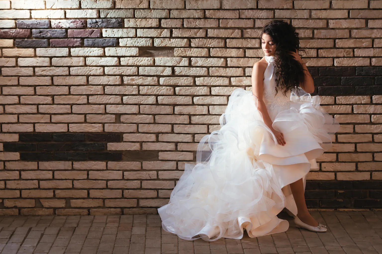 White layered occasion dress against a brick wall